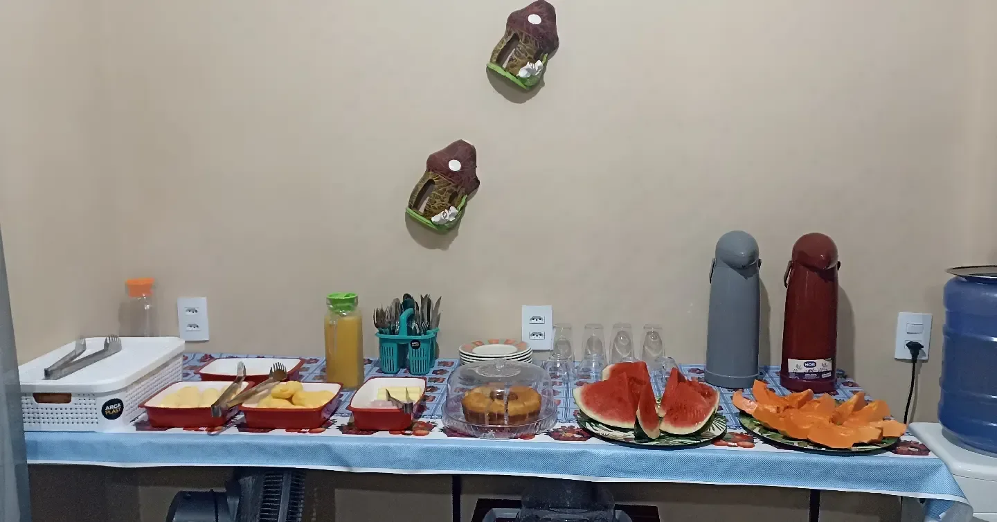 A mesa do café da manhã, com frutas, bolo e suco.