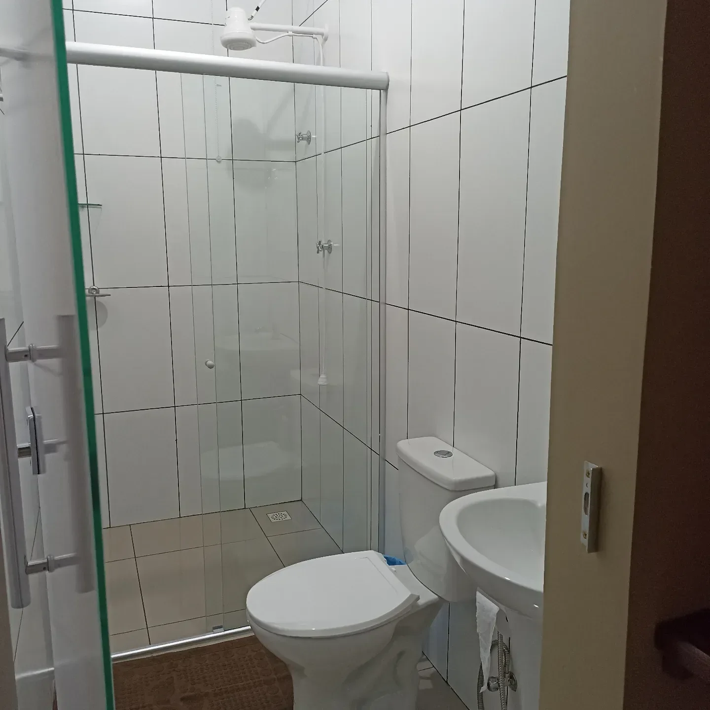 Banheiro com box de vidro, vaso e pia.